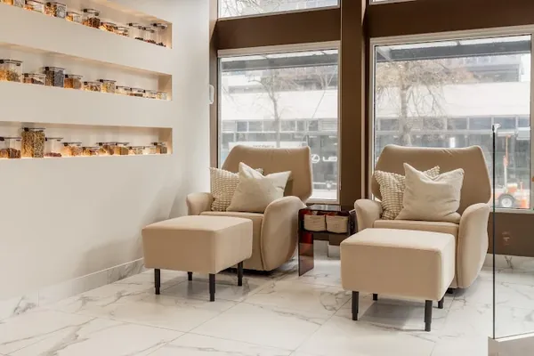 Lounge chairs and a shelf of jars by a window at Knead Kitsilano