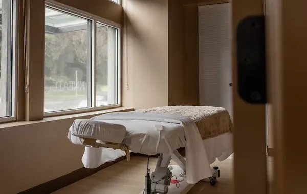 Treatment room with a massage table by a large window