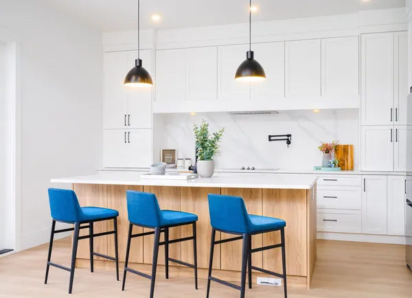 White kitchen with a wood island and blue bar stools