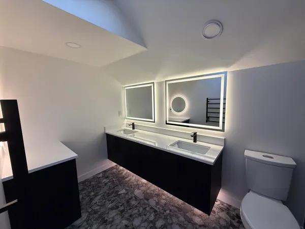 Bathroom with a double floating vanity, backlit mirrors and a lit underside