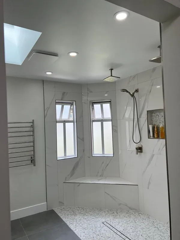 Walk-in tile shower with a bench and two windows
