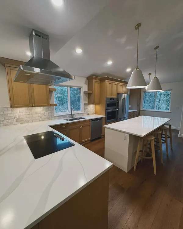 Kitchen with a quartz counter, cooktop and island with stools