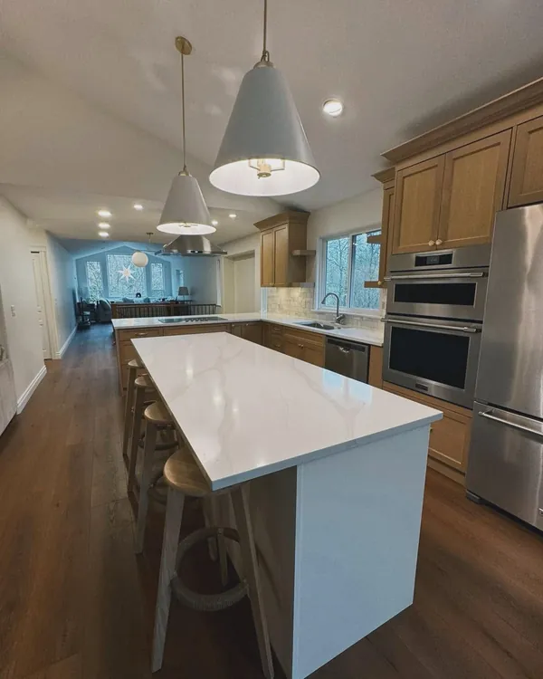 Long kitchen with a white island and pendant lights